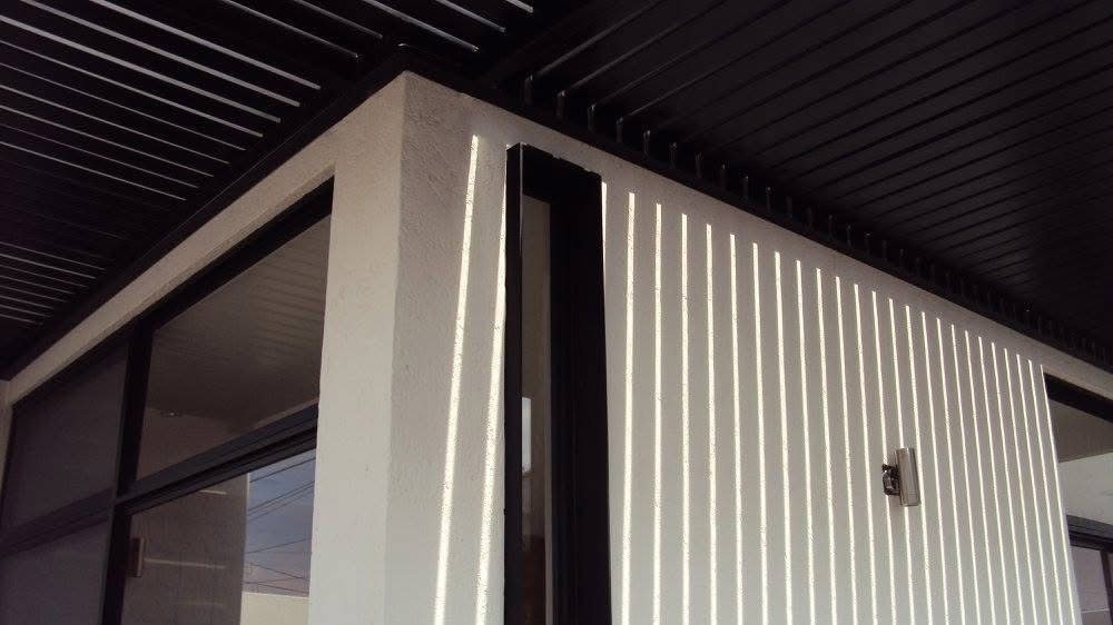 Detalle de celosías verticales y pérgola en fachada