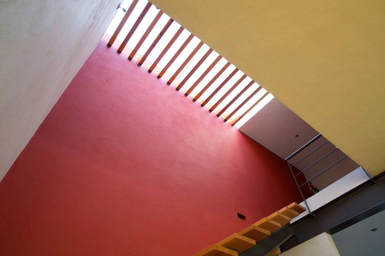 Hueco de escalera con luz cenital y muro rojo